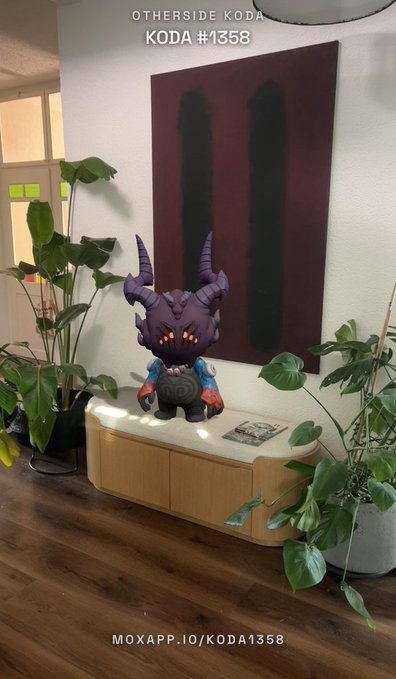 An Otherside KODA NFT (#1358) figurine of a purple-horned character displayed on a wooden cabinet, with the text "MOXAPP.IO/KODA1358" at the bottom.