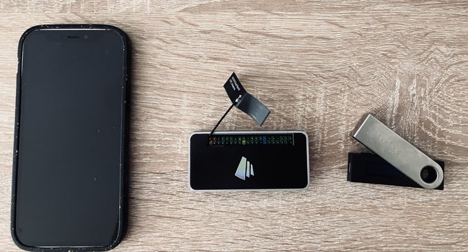 A disassembled smartphone, an old Nokia phone, and a USB flash drive are arranged on a wooden surface.