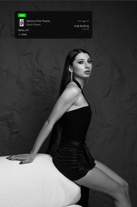 A black and white photograph of a woman in a black halter dress sitting on a white chair, with a Spotify notification for 'Dance of the Thund... Black flower' by Daria_Art showing a 23.00 payment.