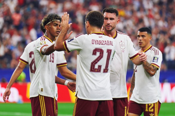 Spanish national team soccer players, including Lamine Yamal (#19) and Oyarzabal (#21), high-five and celebrate during a match while wearing white jerseys with maroon trim.