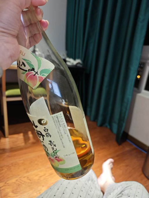 A hand holds up an empty, nearly drained bottle of Japanese umeshu (plum wine), with the label reading "リキュール" (liqueur) and "白鶴梅酒" (Hakutsuru Umeshu), against a backdrop of green curtains. The drained bottle visually mirrors the post's theme of feeling "empty" and "bearish," symbolizing Xin Yi's newfound emptiness and philosophical release after letting go.