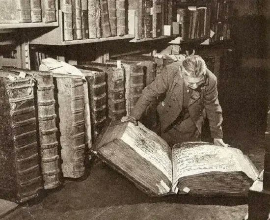 A scholar bends over a massive ancient tome surrounded by towering shelves of leather-bound books, deeply engrossed in search of buried information. The caption humorously captures the feeling of endlessly combing through a dense document to find a single elusive detail.