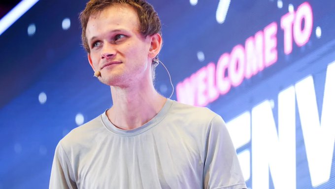 Vitalik Buterin, co-founder of Ethereum, speaks on stage at a conference, wearing a headset microphone and a light-colored t-shirt, with a "WELCOME TO" sign visible in the background. The image aligns with the accompanying post, which highlights his recent comments on PeerDAS, a scaling solution he credits with quietly improving Ethereum's data efficiency for nearly a year.
