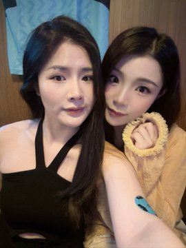 Two young women pose together for a selfie, one wearing a black halter top and the other in a beige sweater, with the arm of a third person visible in the foreground. The caption suggests they are enjoying a lively World Cup viewing gathering with friends sponsored by Bitget.