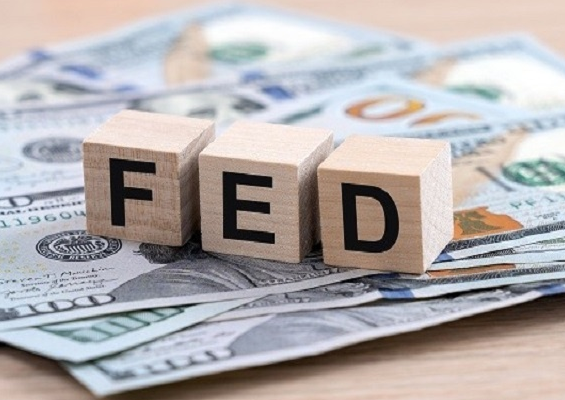 Wooden blocks spelling "FED" rest on a spread of $100 U.S. bills, visually representing the Federal Reserve's anticipated $16.97 billion liquidity injection into the market. The image directly reinforces the post's message about the Fed reopening its liquidity taps, a move expected to fuel risk assets like crypto.