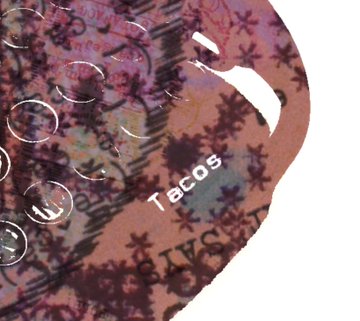 A close-up image of a clear, textured silicone mat or pad with raised bumps and various printed words including 'Tacos' and 'Salsa' visible through the material.