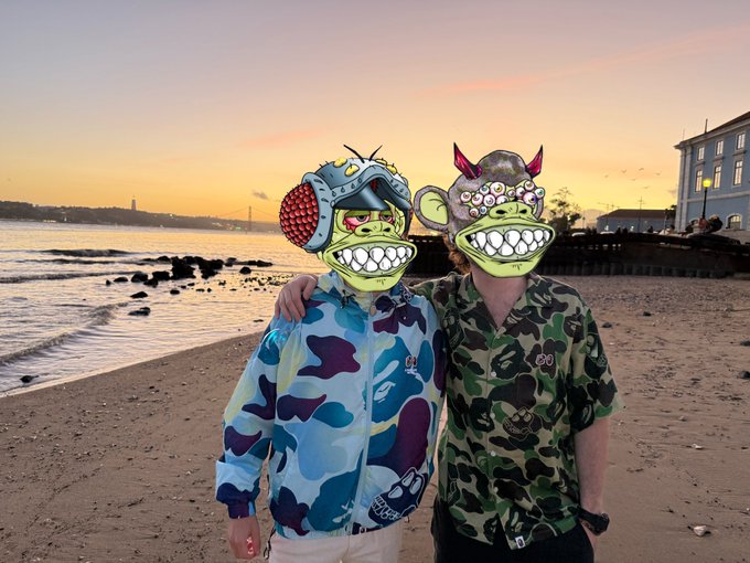 Two people pose on a beach at sunset, their faces obscured by digital Mutant Ape NFT masks—one green with a spiked helmet and the other a zombie-like ape—symbolizing pride in their membership in the Bored Ape Yacht Club community.