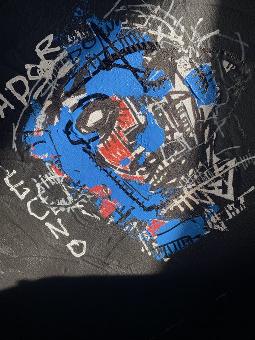 Street art/graffiti on a black surface featuring an abstract design in blue, red, and black, with the text 'APRIL' and 'LEGEND' written in white spray paint, along with a white heart symbol.