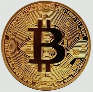 A gold-colored Bitcoin commemorative coin featuring the iconic "₿" symbol with circuit-like patterns and partially visible text including "DIGITAL," "PEER TO PEER," "DECENTRALIZED," and "FINE COPPER" around its edge. The coin visually represents the Bitcoin choice mentioned in the post, symbolizing the legendary cryptocurrency created by Satoshi Nakamoto.