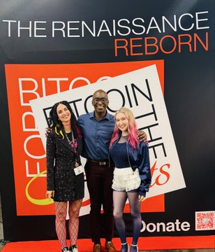 Three people posing together in front of a step-and-repeat backdrop reading "THE RENAISSANCE REBORN" and "BITCOIN PEOPLE" with "Donate" and a QR code visible at the bottom.