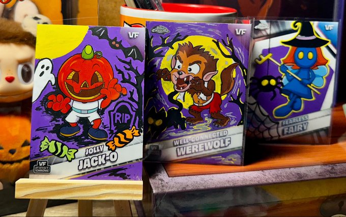 Three Halloween-themed collectible cards displayed on wooden stands: 'JOLLY JACK-O', 'WELL-CONNECTED WEREWOLF', and 'FEARLESS FAIRY' by V.F., with a Funko Pop figure visible in the background.