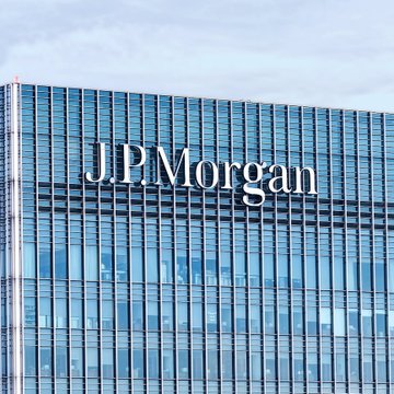 A modern glass office tower displays the prominent sign “J.P. Morgan.” The image relates to the accompanying post’s claim that J.P. Morgan Asset Management expects Bitcoin to return 10% annually over the next 10–15 years.
