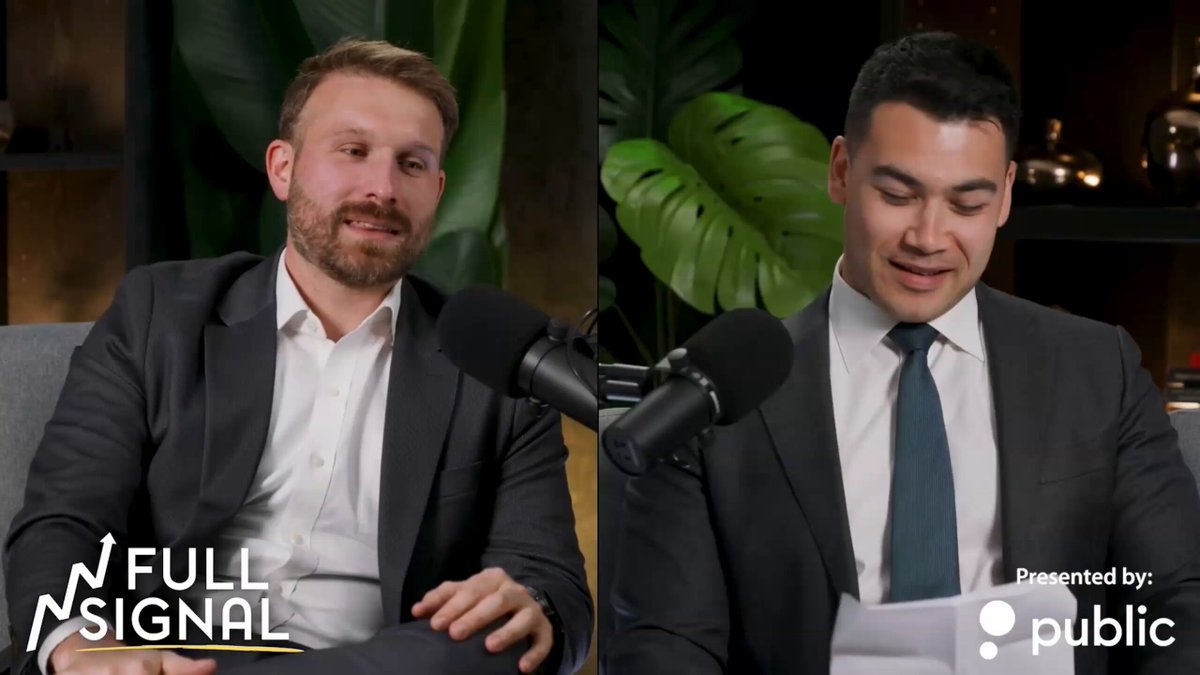 The image shows two men wearing suits sitting next to each other with microphones in front of them. They appear to be having a conversation, possibly discussing Bitcoin or related topics. The background features a plant, adding a touch of nature to the scene. The text on the image includes mentions of Bitcoin and AI stocks, suggesting that they might be talking about cryptocurrency or artificial intelligence markets.