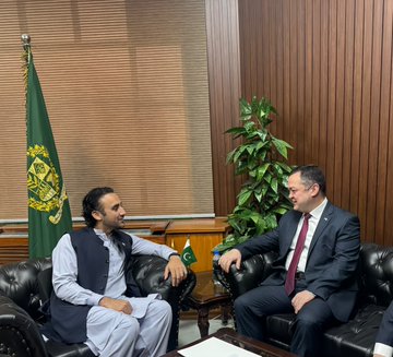 Bilal BinSaqib, Chairman of the Pakistan Virtual Assets Regulatory Authority (PVARA), sits in conversation with Uzbekistan's Ambassador to Pakistan, Alisher Tukhtaev, in a formal meeting room adorned with the Pakistani flag at the Prime Minister's Office in Islamabad.