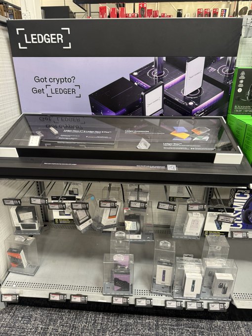 A retailer display for "LEDGER" hardware crypto wallets with the text "Got crypto? Get [LEDGER]" and shelves of the products below.