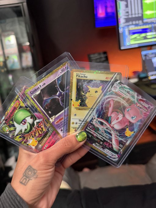 A hand with green nail polish holding four Pokémon trading cards including Gardevoir, Crobat, Pikachu, and a pink Mew VSTAR, displayed in protective sleeves.