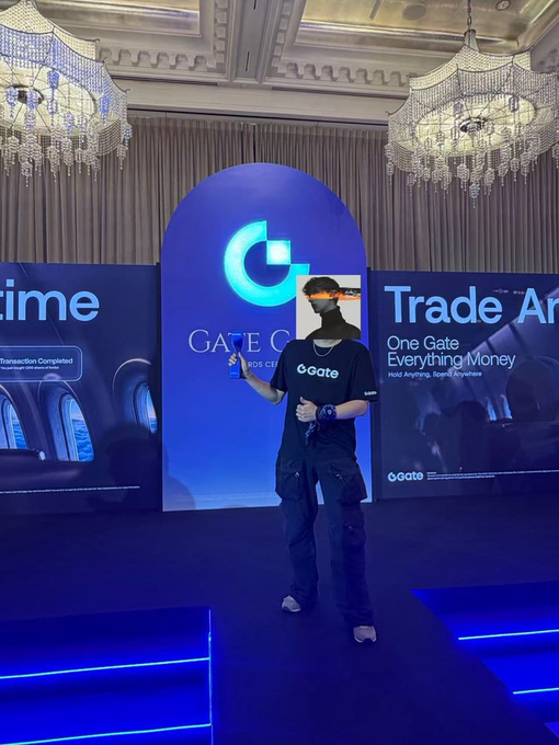 A man stands on a stage at a Gate.io "Trade Anytime" crypto exchange event, with the Gate logo and tagline "One Gate, Everything Money" visible behind him. The image complements the post celebrating "Brother Lu" as Gate's best employee by showing the man likely being honored or recognized at the company's promotional event.