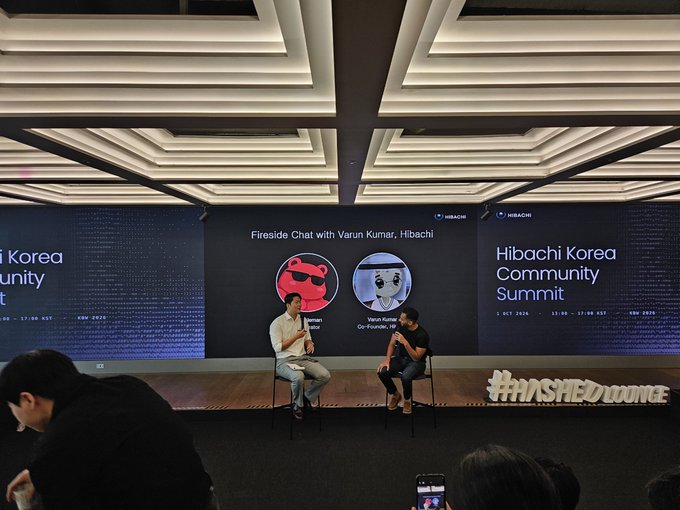 Two men sit on stools having a 'Fireside Chat with Varun Kumar' on stage at the Hibachi Korea Community Summit, with the hashtag #HASHEDLOUNGE displayed.