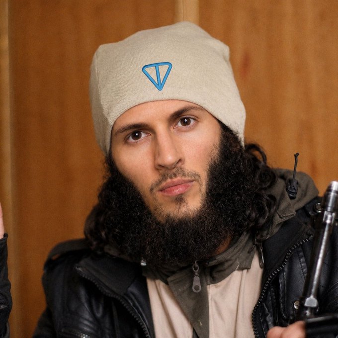 A man with a long beard wearing a beanie featuring a blue "TON" (The Open Network/Telegram cryptocurrency) logo holds what appears to be a firearm, visually reinforcing his post about funding a TON wallet address for a cryptocurrency investment opportunity.

Note: The image appears to be a known photo of Michael Malice, and the combination of an armed threat with a crypto investment pitch is a well-documented scam tactic.