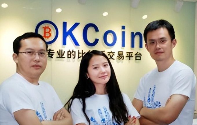 The image features three people standing together, with two men wearing white shirts and a woman wearing a blue shirt. They are posing for a photo in front of a large sign that says "OK Coin" written in Chinese characters. The group appears to be from China or is interested in Chinese culture, as they are all dressed similarly.