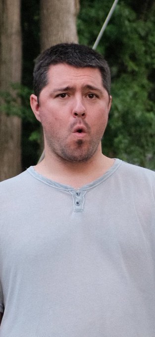 A man in a gray henley shirt stands outdoors with a stunned, speechless expression—his mouth open in awe and eyes wide—perfectly capturing the "I can't believe this is happening" reaction to minting a 1/1 NFT.