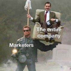 A famous 'guy carrying a couch' meme edited to include the text 'Marketers' pointing to a man with a gun and 'The entire company' on the couch being carried.