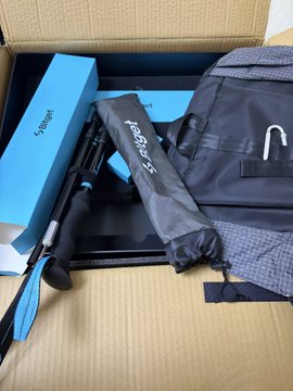 An open cardboard box containing hiking or travel gear, including blue product boxes labeled 'XCOOGER' and black carrying bags/pouches.