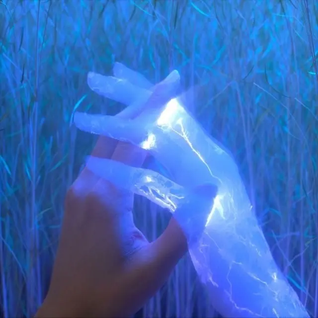 A glowing blue ethereal hand reaches through a background of illuminated blue grass or branches, creating a mystical, otherworldly scene.