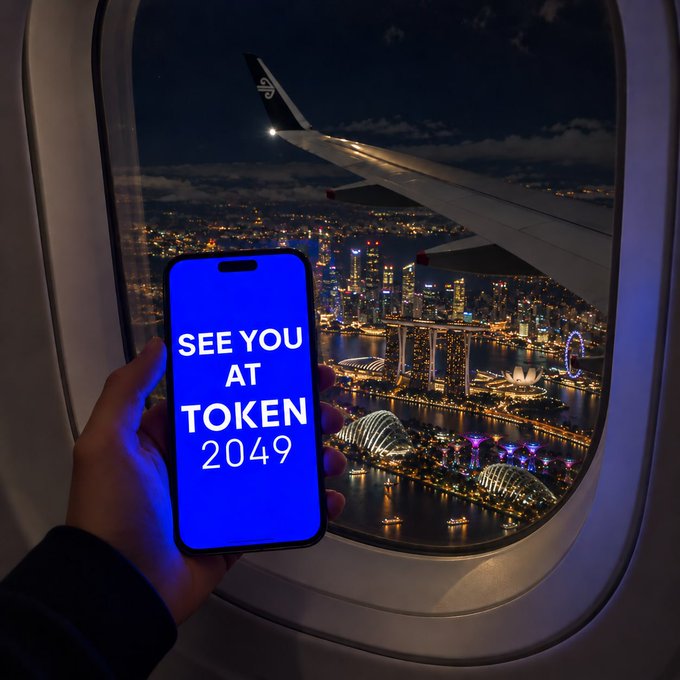 A hand holds up a phone displaying 'SEE YOU AT TOKEN 2049' in blue light, with Singapore's Marina Bay skyline and an airplane wing visible through the window.