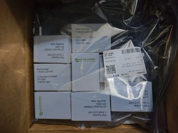 A photograph of several small white boxes labeled 'Panasonic LCR' components sealed inside a clear plastic bag inside a cardboard shipping box.