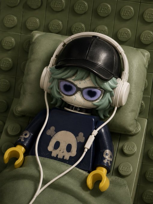A LEGO minifigure styled like an anime character with green hair, skull face paint, a black cap, white headphones, and a dark blue skull-printed shirt, resting against a green LEGO baseplate background.