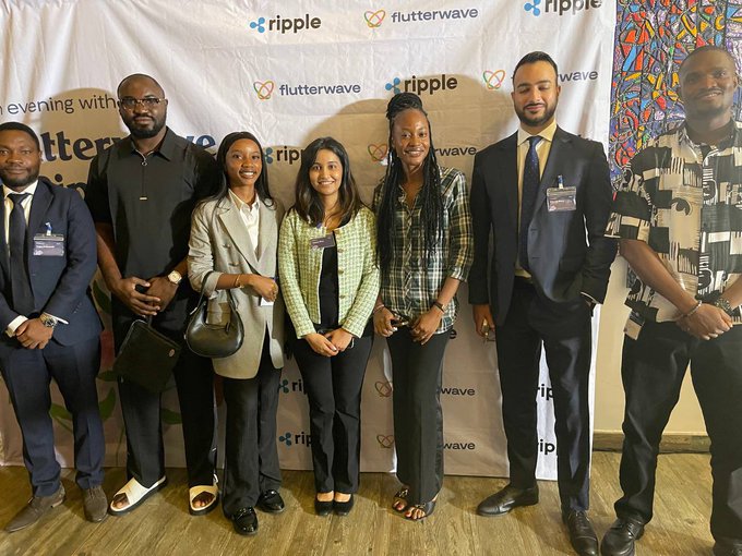 A group of eight people posing together in front of a step-and-repeat backdrop featuring 'ripple' and 'flutterwave' logos, suggesting a Flutterwave corporate event.