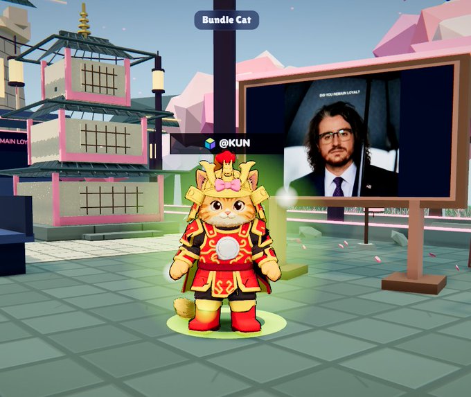 A virtual 3D cat character dressed in red and gold samurai armor stands labeled 'Bundle Cat' in a colorful game world with a pagoda and a screen showing a man's face.