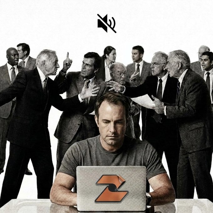 A man sits focused on a laptop with a Z logo while behind him a group of older men in suits argue heatedly, with a muted speaker icon above his head.