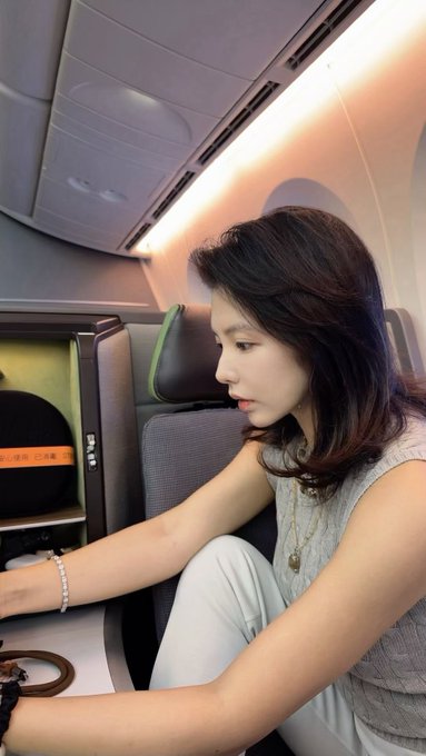 A young woman sits in an airline seat, gazing thoughtfully downward as if contemplating the future. Her reflective pose pairs with the post's speculative question about Ethereum versus Solana, suggesting she's pondering which cryptocurrency will hold greater value in the years ahead during her travels.