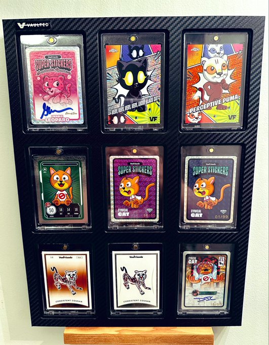 The image features a black frame displaying nine different cat-themed trading cards, each with unique designs and colors. The cards are arranged in a grid pattern within the frame, showcasing various cats from different breeds and sizes. The post includes text that reads "MEOW Obsessed with my @veefriends cats & IRL kitties!! #gratefulheart Collect." This suggests that the person who posted this image is an avid collector of cat-themed trading cards or merchandise related to cats, such as toys, accessories, and artwork. The post also mentions a "Collector" theme, which indicates that the person might be part of a community or group sharing similar interests in collecting cat-related items.