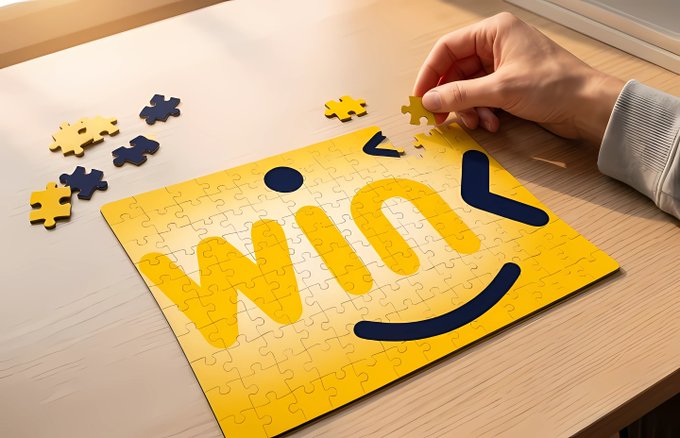 A hand places a yellow puzzle piece onto a nearly completed yellow jigsaw puzzle featuring a dark blue smiley face design, with a few scattered pieces nearby on a wooden table.