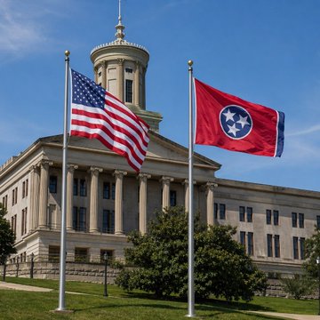 The image shows the Tennessee State Capitol building in Nashville, with the American flag and Tennessee state flag flying on flagpoles in the foreground under a clear blue sky. The caption relates to the post by symbolizing the seat of Tennessee state government, where decisions like Hawkins County commissioners' 12-0 vote to ban crypto mining facilities and data centers would have broader political context and implications.