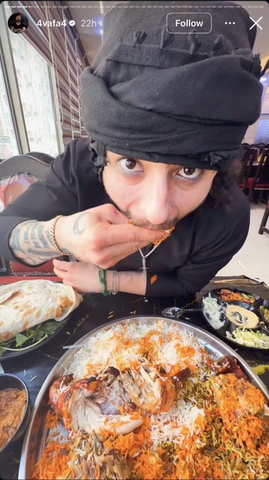 A man wearing a black head covering leans over a large platter of rice and meat, eating with his hands. The image is an Instagram story from user '4vafa4' posted 22h ago.