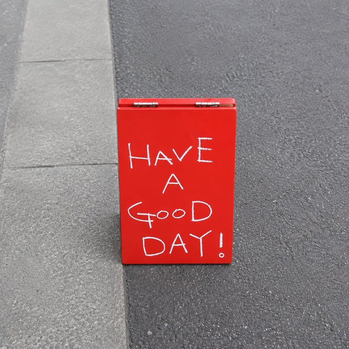 A red box on pavement with white handwritten text reading 'HAVE A GOOD DAY!'.