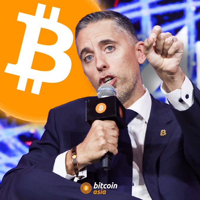 The image features a man wearing a suit, holding a microphone, and talking into it at an event or gathering. He appears to be a speaker or presenter engaging with the audience. In the background, there are orange Bitcoin symbols representing Bitcoins, indicating that this may be related to the world of digital currency. The accompanying post mentions that a public company called Strive has purchased 32 Bitcoin for $2.1 million and is planning to keep the Bitcoins stacked. This information suggests that the event or gathering could be related to discussions about blockchain technology, cryptocurrency, or financial markets. The man speaking might be providing insights into Strive's position on Bitcoin investments or offering updates on the digital currency market as it progresses.
