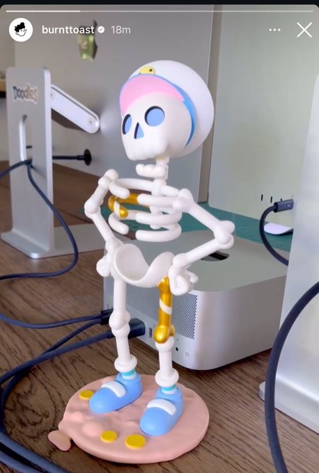 An Instagram story screenshot from 'burnttoast' showing a 3D-printed skeleton figurine wearing a pink and blue duck-themed cap and blue shoes.