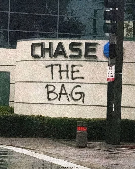 A photograph of a Chase bank building sign that has been defaced with graffiti reading 'THE BAG' beneath the Chase logo, watermarked 'Above Average Club'.