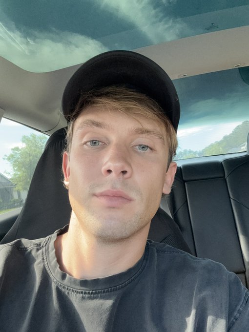 A young man wearing a black cap and dark t-shirt takes a selfie inside a car with a panoramic glass roof, looking directly at the camera with a neutral expression. The "GM GM Web3" post likely uses his casual, relaxed look as a relatable web3 greeting, with the sunrise through the car roof symbolizing a fresh start in the crypto community.