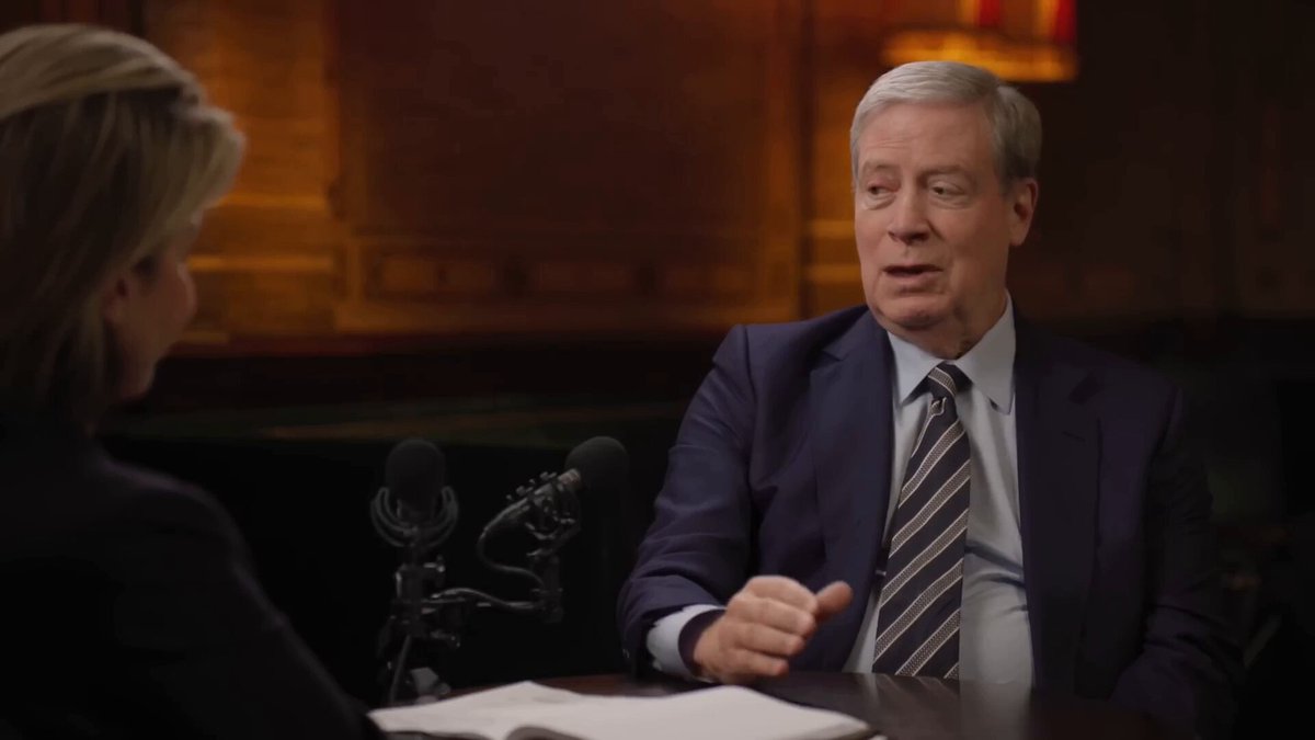 The image shows a man wearing a suit and tie sitting at a table with another person across from him, engaged in conversation. The background features a wooden wall that adds an elegant touch to the scene. The image also includes text elements such as "ETH investor Stanley Druckenmiller" and " Founders", which may be related to the post's content about the ETH treasury company or its founder, Tom Lee.