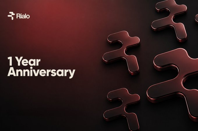 Dark red 3D-style advertisement for Rialo featuring puzzle piece graphics and text announcing a "1 Year Anniversary."