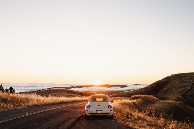 𝕏 family In the beginning and in the end, the soul will be in the middle of the @base Are you still posting about $BASE?". The image features a white car driving down an empty road with a beautiful sunset behind it.