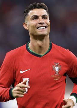 Soccer player Cristiano Ronaldo smiling in a red Portugal national team jersey.