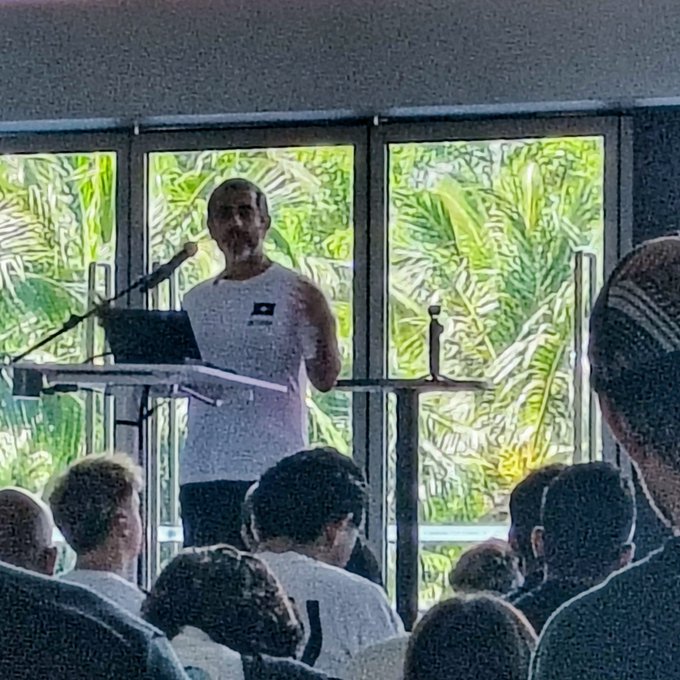 The image shows a man standing at a podium, giving a speech or presentation to an audience of people who are seated behind him. The man appears to be wearing a white shirt with a logo on it. There are several people sitting in chairs around the room, and some are looking directly at the camera while others are facing away from it. In addition to the speaker, there is also a laptop visible near the podium.

The post that accompanies this image reads: "Balaji just gave Zcash Network School a shout-out NS.com/Zechariah/apply $ZEC". This suggests that the man giving the speech might be an employee or representative of Zcash, and he is acknowledging the audience for their support or participation in his presentation.