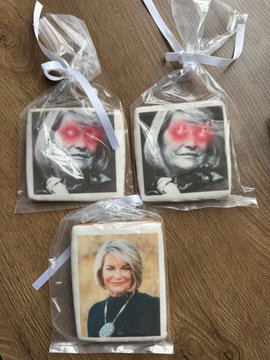 Three custom-printed cookies in clear gift bags with white ribbons, decorated with portraits of Hillary Clinton wearing heart-shaped sunglasses and another woman with a turquoise necklace.